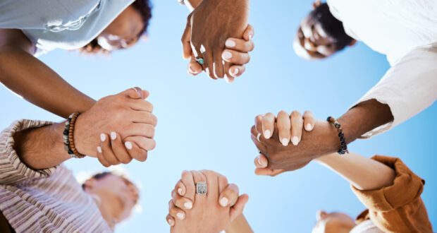 Diversity, support and people holding hands in trust and unity for community against sky background. Hand of diverse group in solidarity for united team building collaboration and teamwork success.